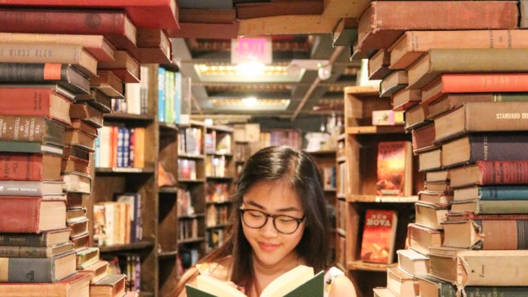 woman in green shirt sitting on books