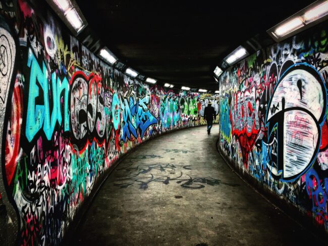 man walking on hallway with graffiti walls