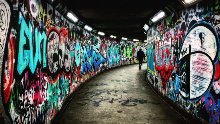 man walking on hallway with graffiti walls