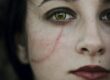 a close up of a woman's face with blood on her cheek