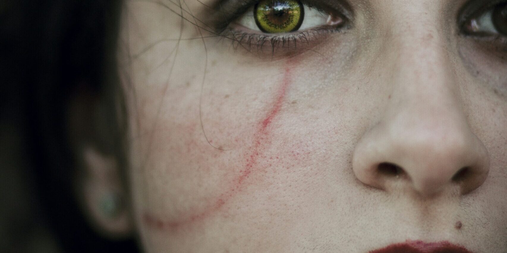 a close up of a woman's face with blood on her cheek