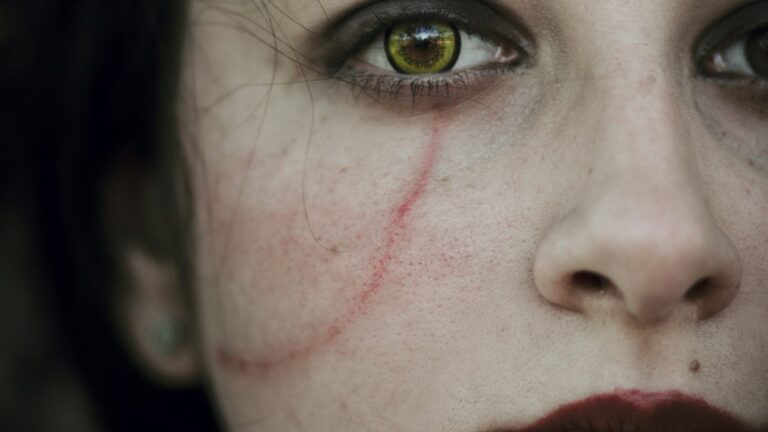 a close up of a woman's face with blood on her cheek